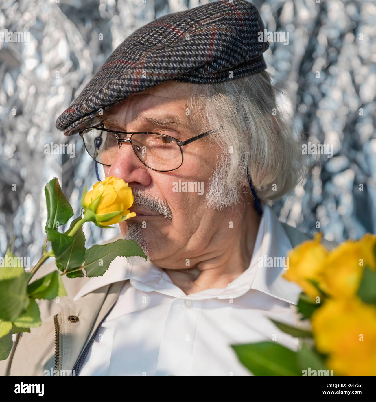 happy pensioner smells a yellow rose Stock Photo