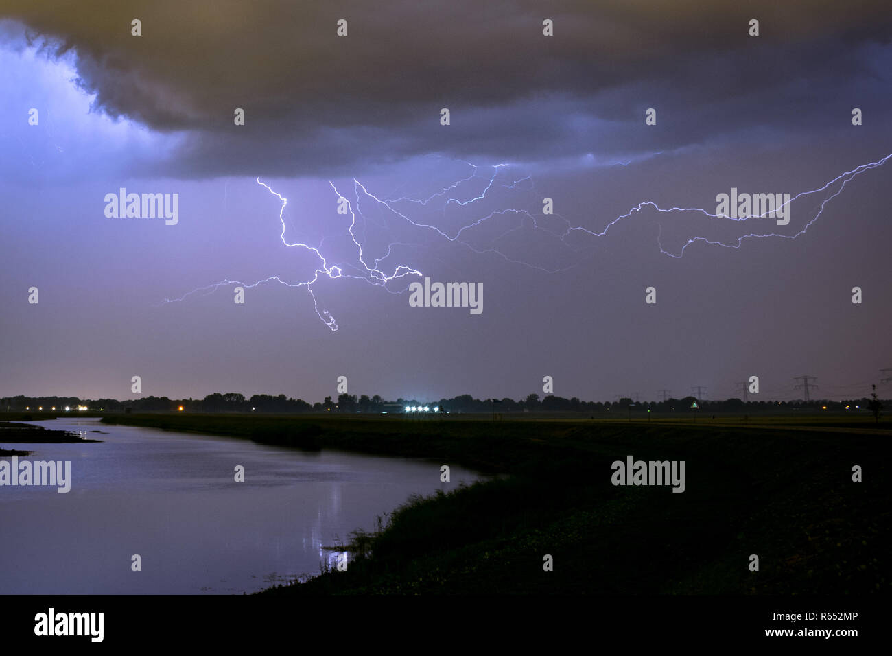 Lightning bolts in the sky over a lake in the vicinity of Rotterdam, The Netherlands.  Photographed during a severe summer thunderstorm. Stock Photo