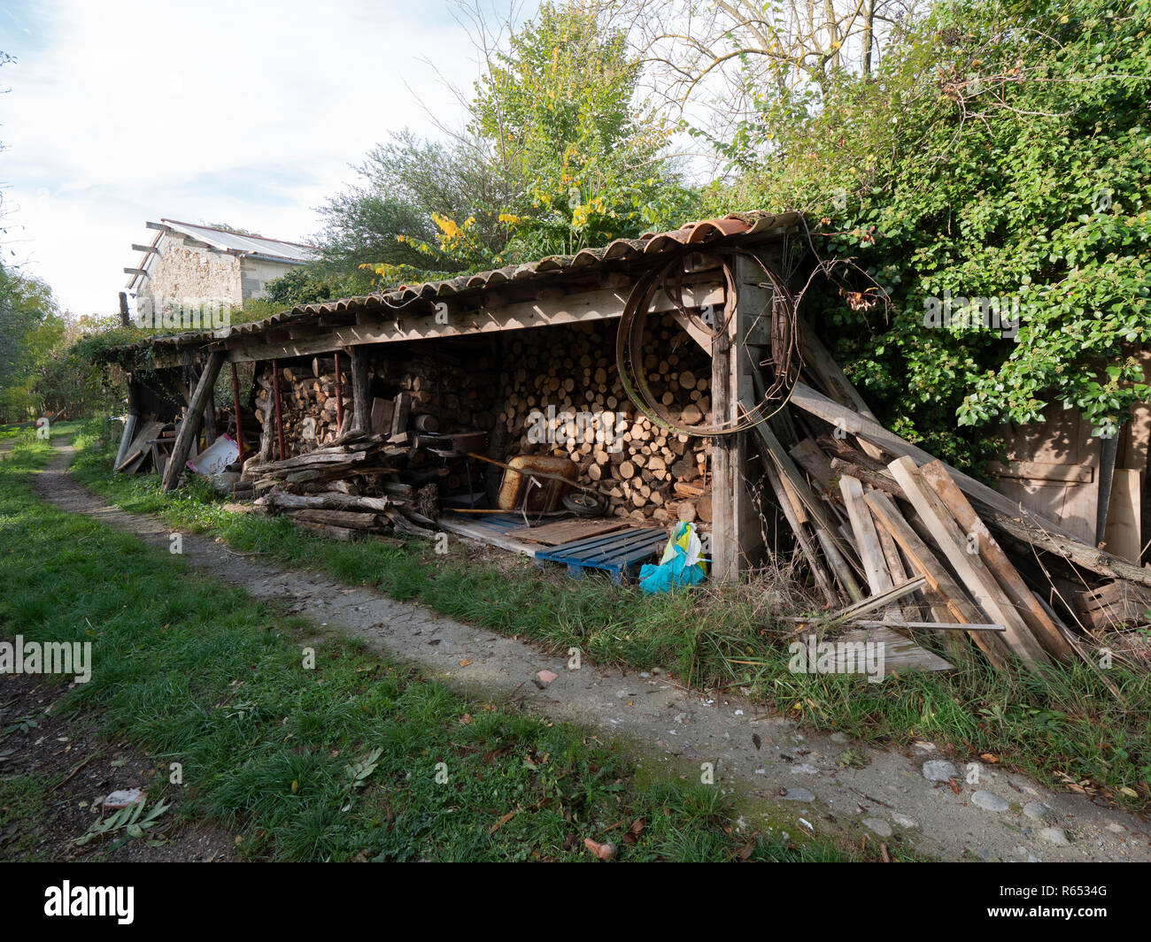 Rural scene of woodshed with metal wheel treads and wheelbarrow in