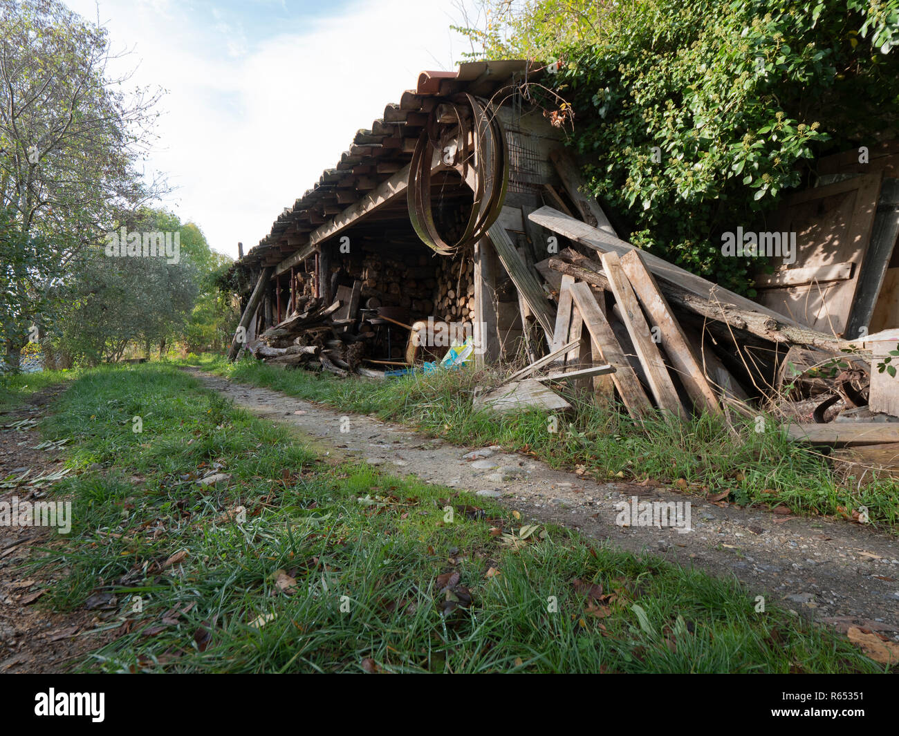 Rural scene of woodshed with metal wheel treads and wheelbarrow in