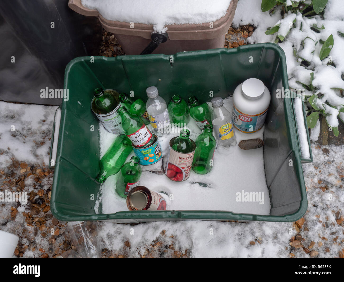 Green recycling bin with snow, beer bottles, cans and containers Stock