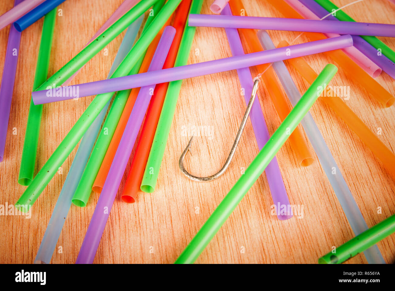 Fishing hook surrounded by drinking straws, a concept of the pollution