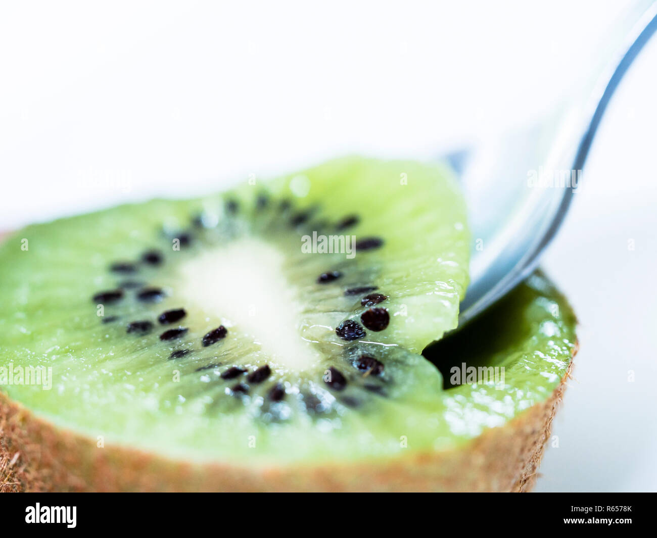 Spooning centre of sliced kiwi fruit Stock Photo