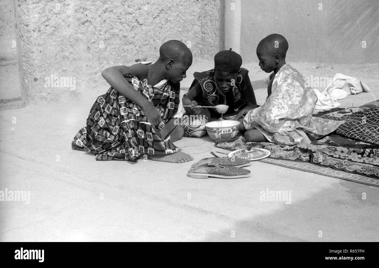 Nigeria Africa 3 young boys sharing food together 1950s Stock Photo