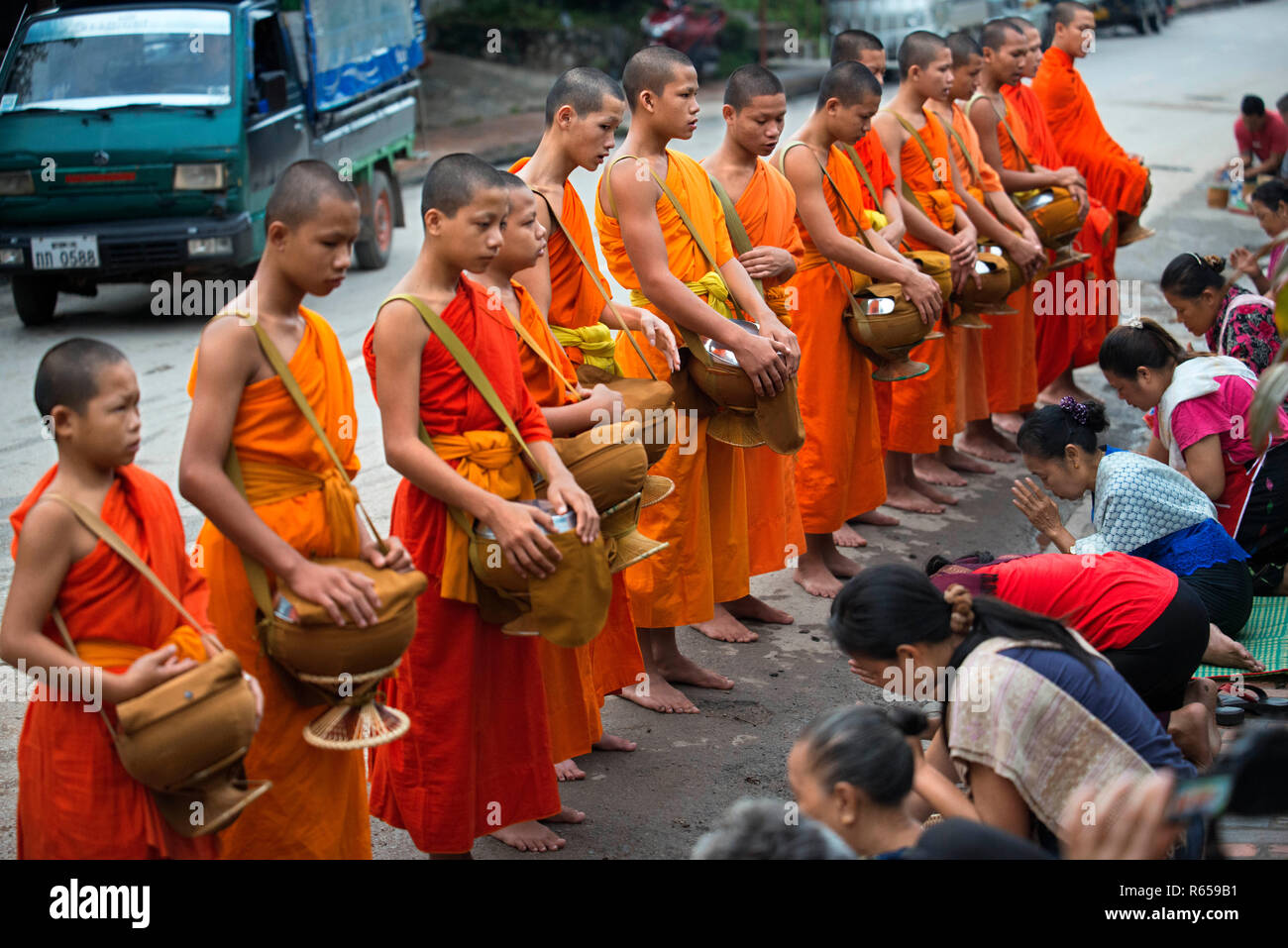 Tak bat ritual - Buddhist monks receive rice and food from pupulation in early morning in Luang Prabang , Laos, Asia Stock Photo