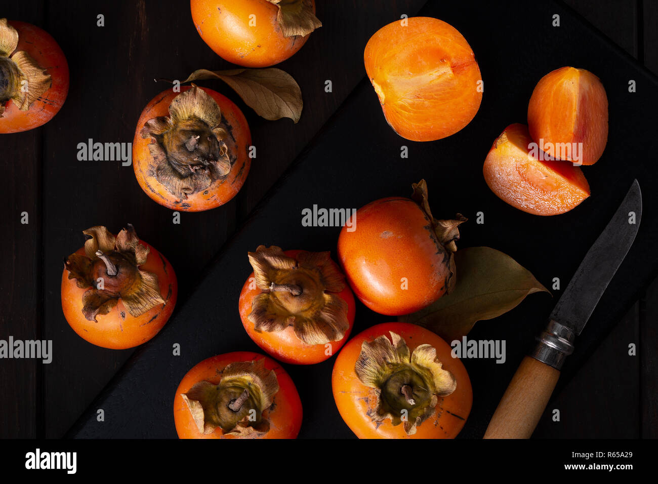 Persimmon still life in a low key. Organic Kaki fruit harvested in autumn. Top view. Diospyros kaki Stock Photo