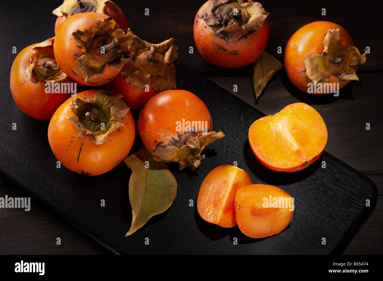 Persimmon still life in a low key. Organic Kaki fruit harvested in autumn. Top view. Diospyros kaki Stock Photo