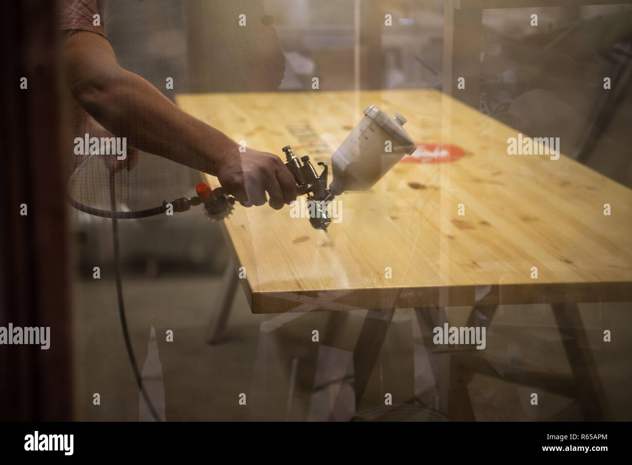 Master painter in a factory industrial painting wood with spray gun