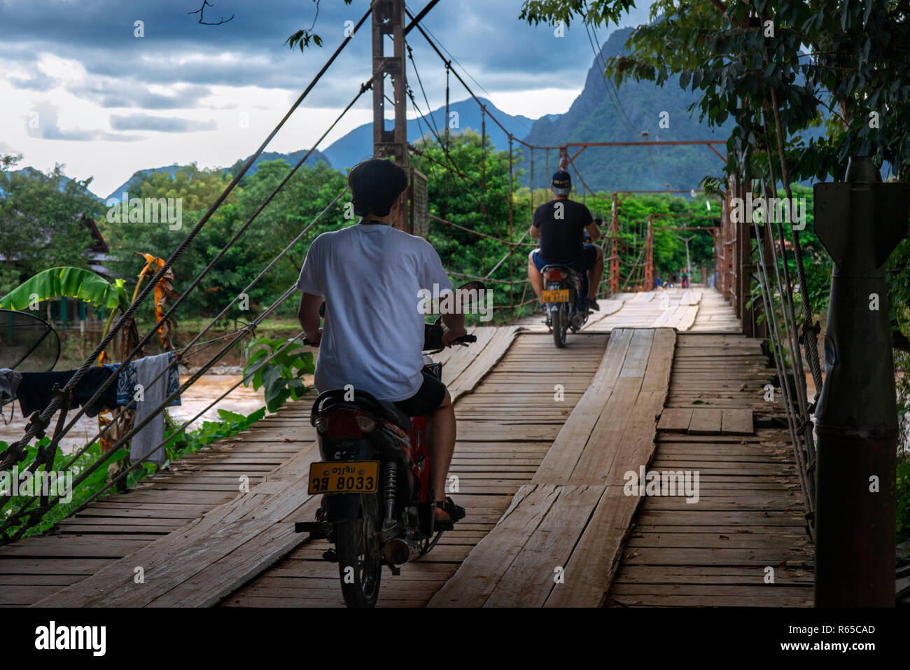 Motorcycle crossing wooden bridge across Nam Song river at Vang Vieng, Laos Stock Photo