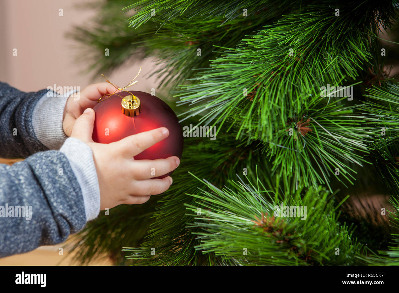 Baby boy decorates Xmas Tree with red ball Stock Photo Alamy