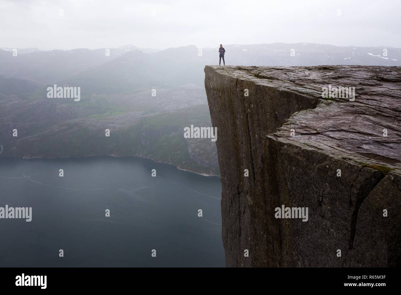 happy girl hiker standing on Preikestolen and looking at the mountains