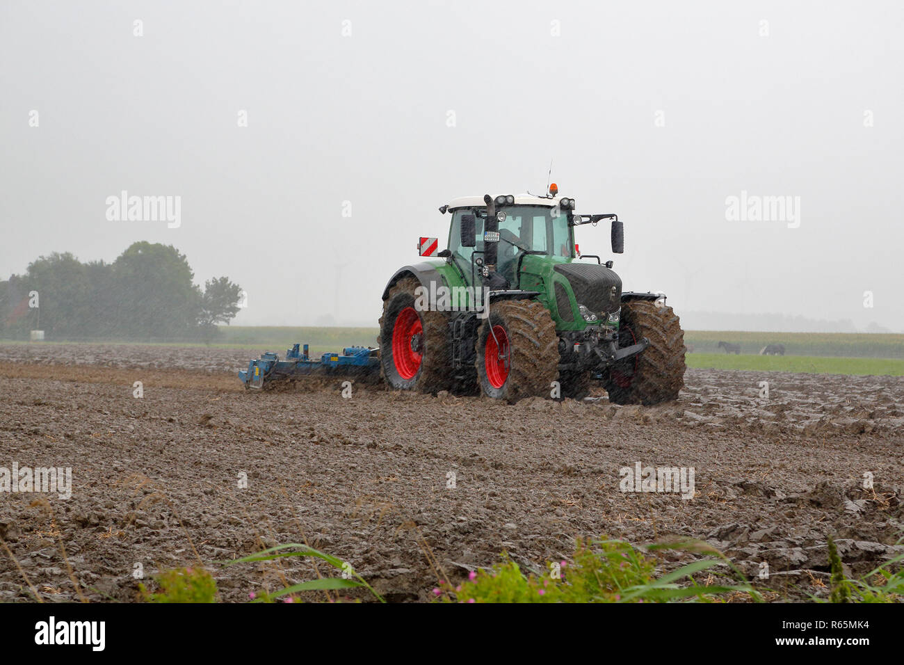 tractor harrowing in heavy rain Stock Photo