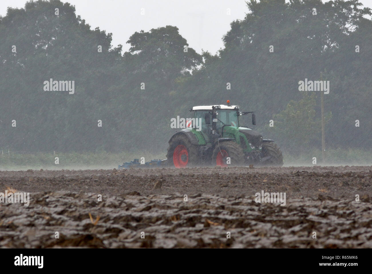 tractor harrowing in heavy rain Stock Photo