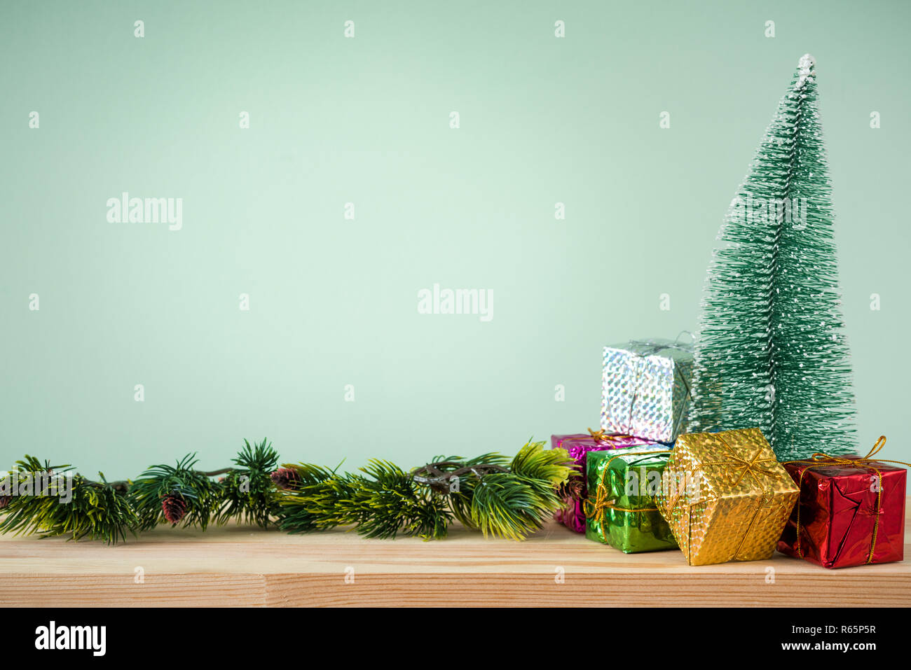Christmas background. A small Christmas tree and boxes with gifts on a wooden table. Green background. Space for text. New Year's background. Stock Photo
