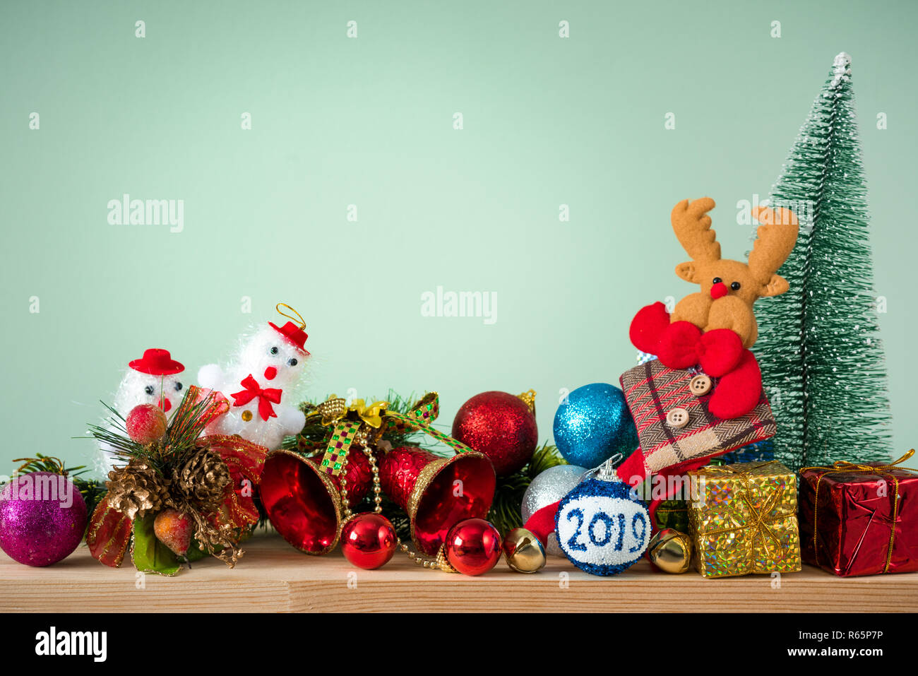 Christmas background. A small Christmas tree and boxes with gifts on a wooden table. Green background. Space for text. New Year's background. Stock Photo