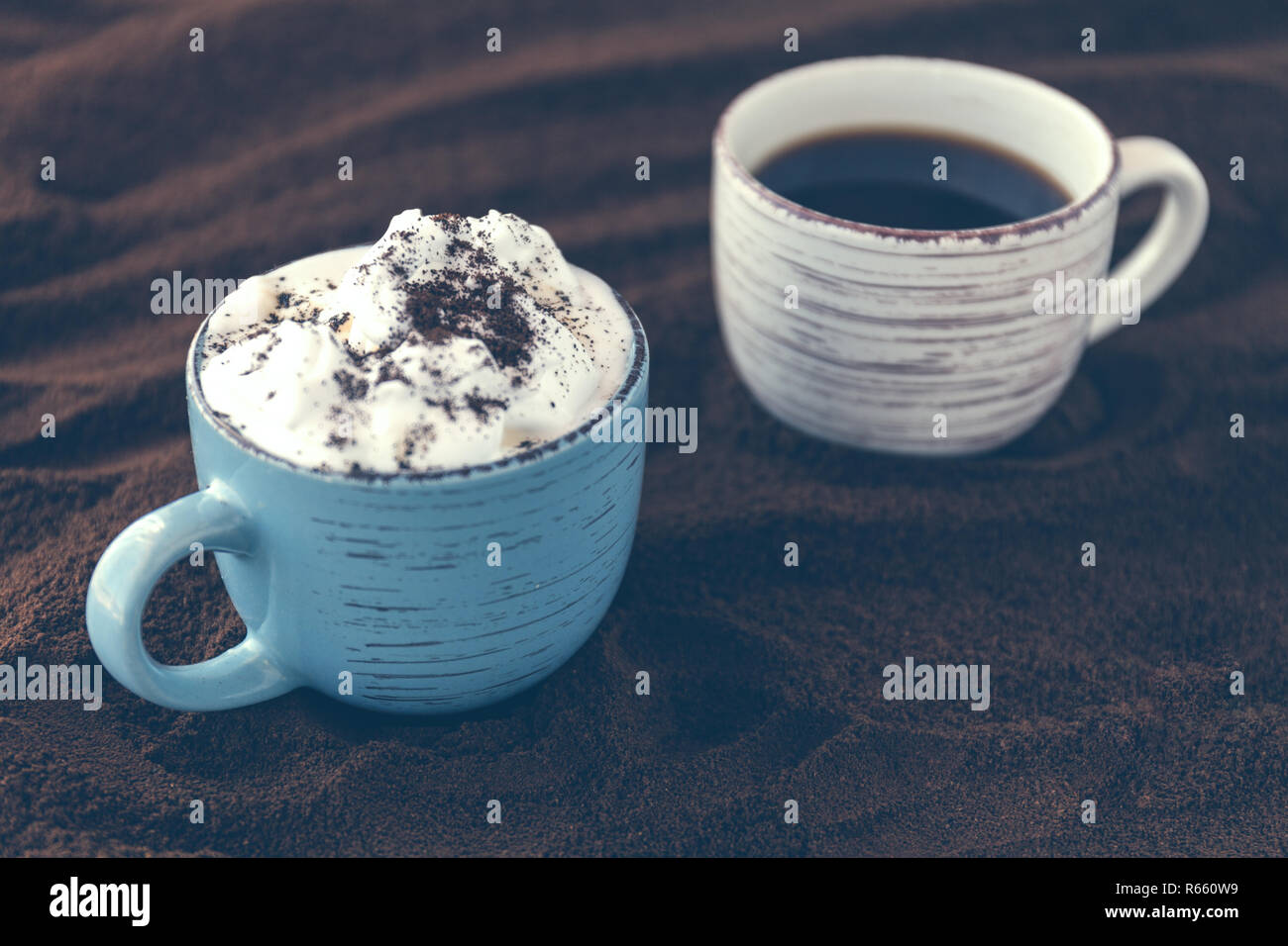 Closeup of tasty coffee and whipped cream. Cups on a table covered with ground coffee. Fog filter effect Stock Photo