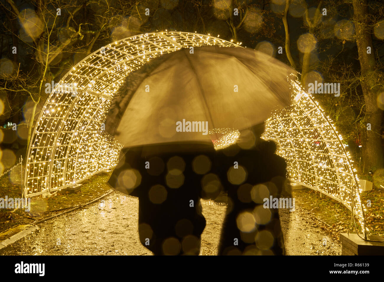 couple in the night light in the rain in front of the light tunnel Stock Photo