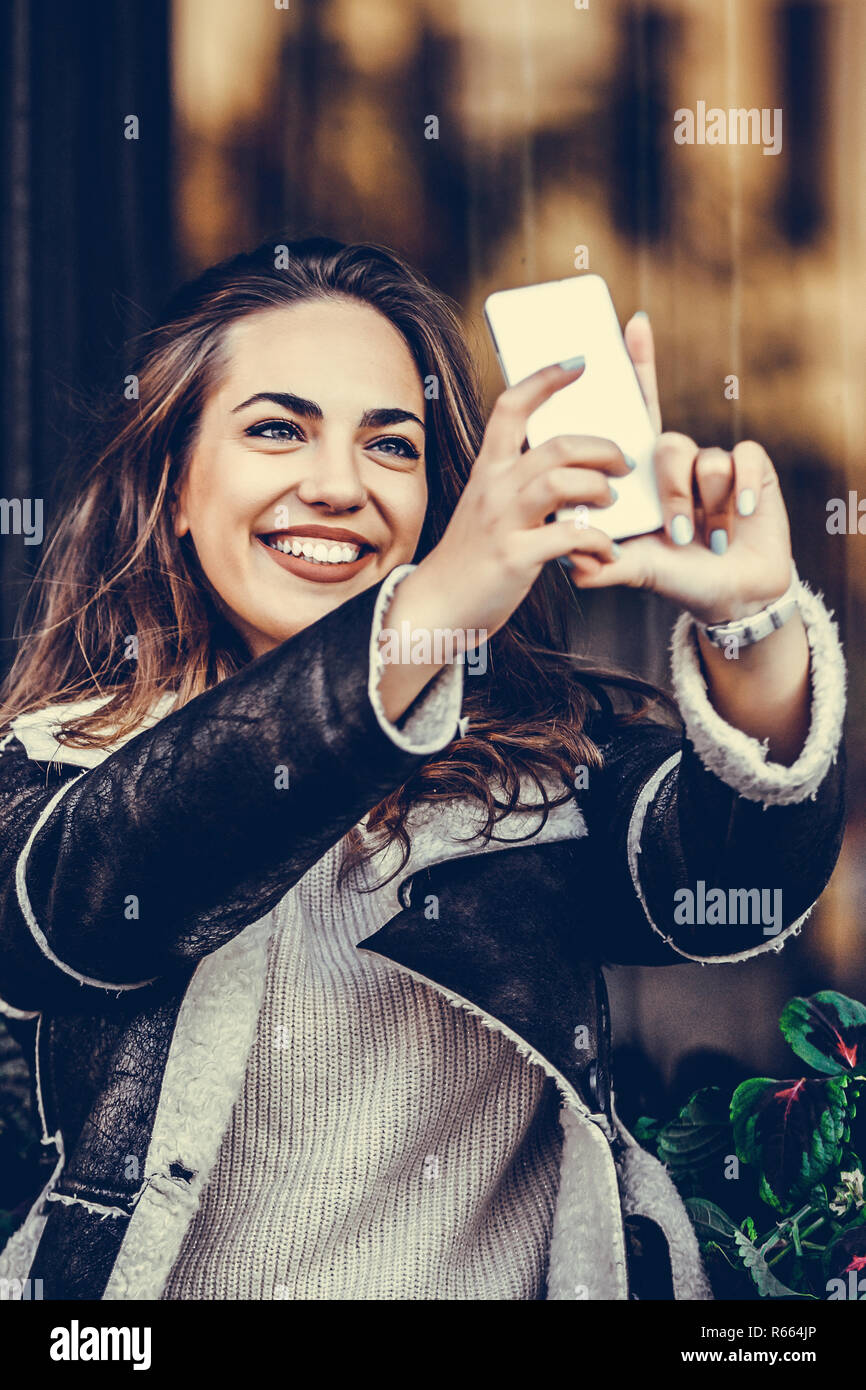 Smiling young woman making selfie photo on smartphone in the city street Stock Photo