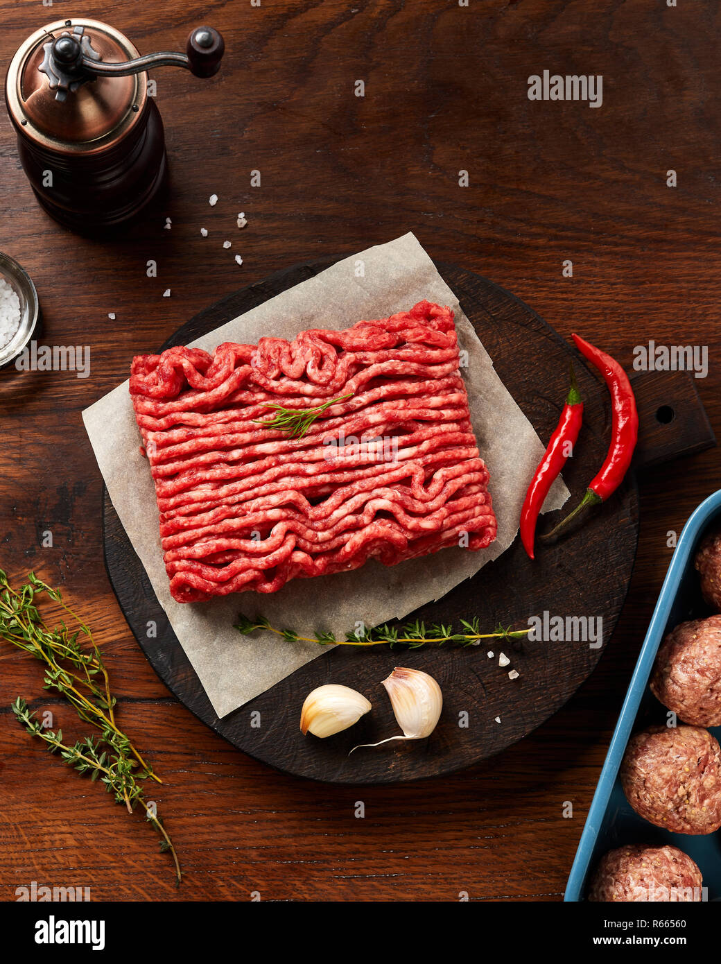 Minced beef meat and meatballs with salt, garlic, herbs on wooden table