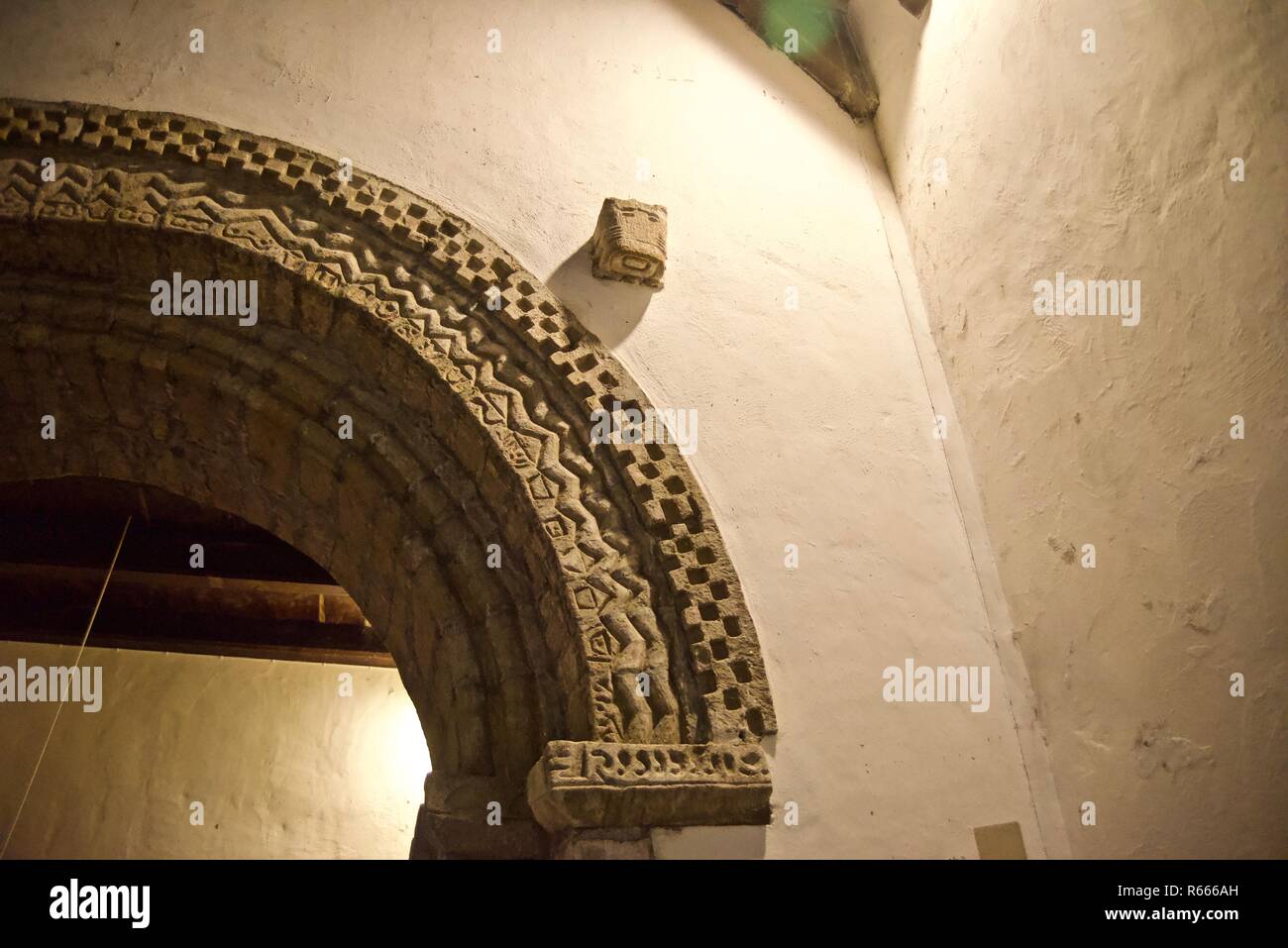 Carved detail on stone arch in interior view of Penmon Priory St Seiriol's Church, Anglesey, Wales, UK Stock Photo