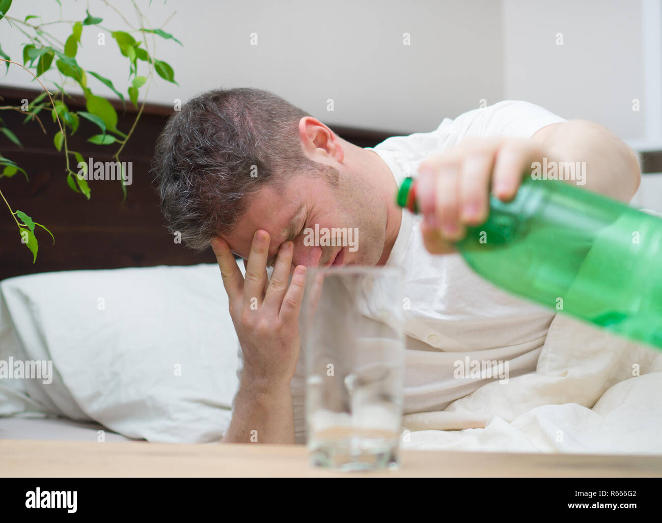 Man drinking mineral water and suffering from hangover Stock Photo Alamy