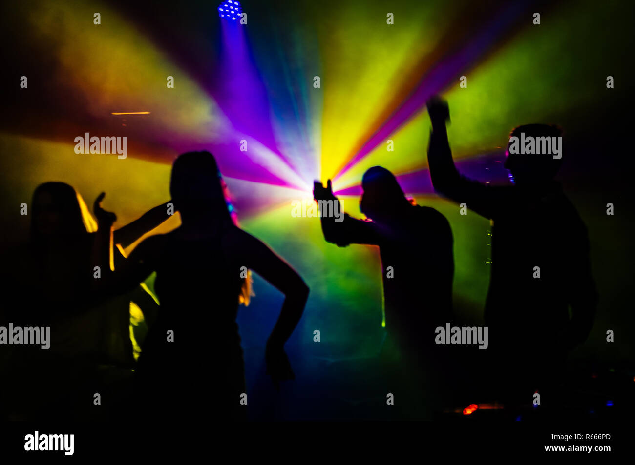 Male and Female dancers silhouetted by the lights in the night club. Stock Photo