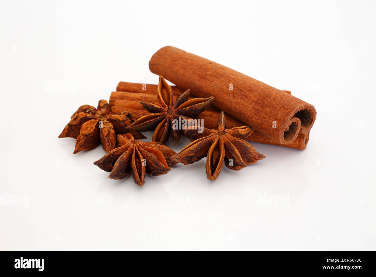 Cinnamon sticks and star aniseed on white reflective background. Selective focus. Macro. Stock Photo