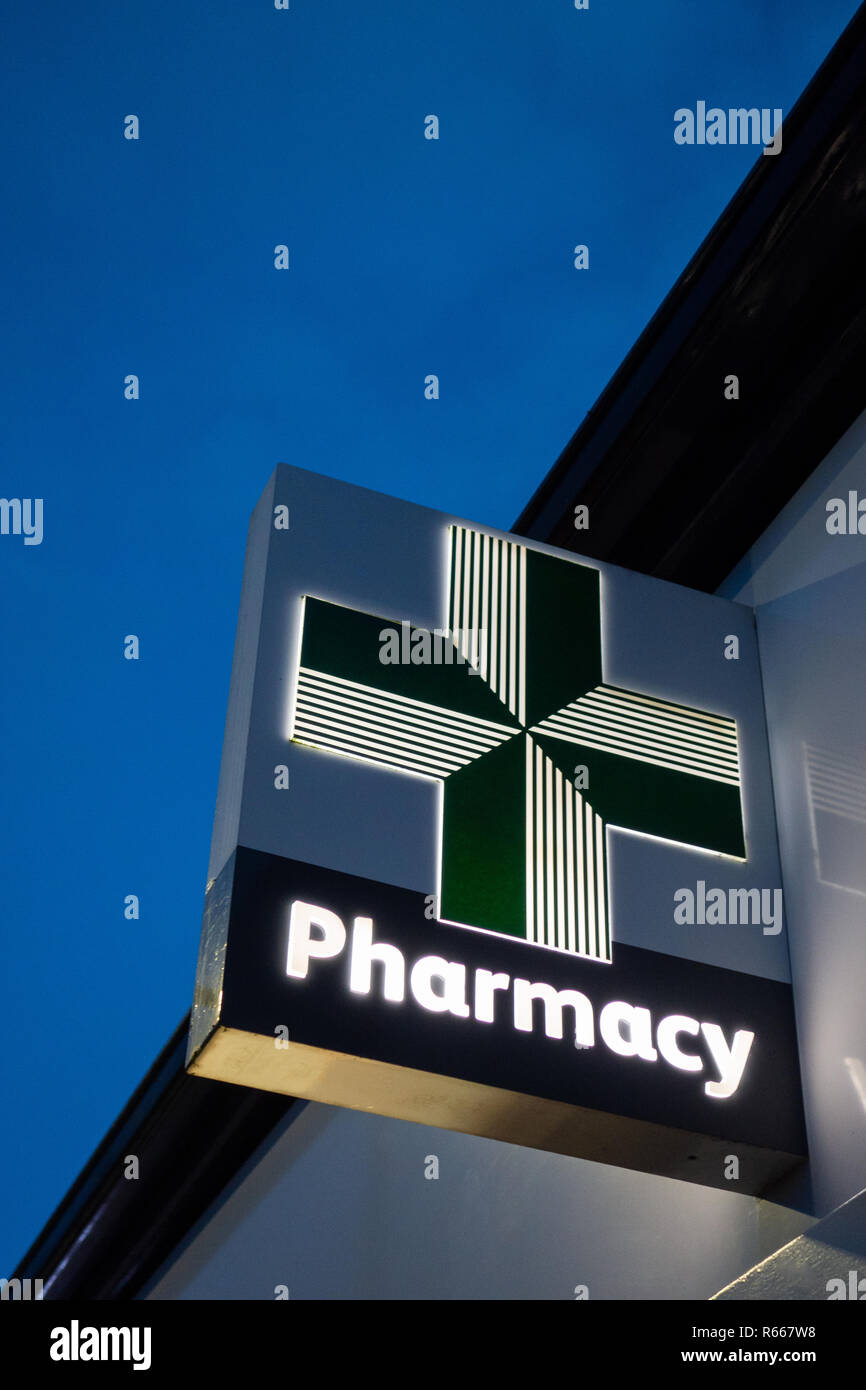 Close up of a illuminated Green Medical pharmacy Cross at Lloyds chemist sign at dusk in Dinnington, Rotherham UK Stock Photo