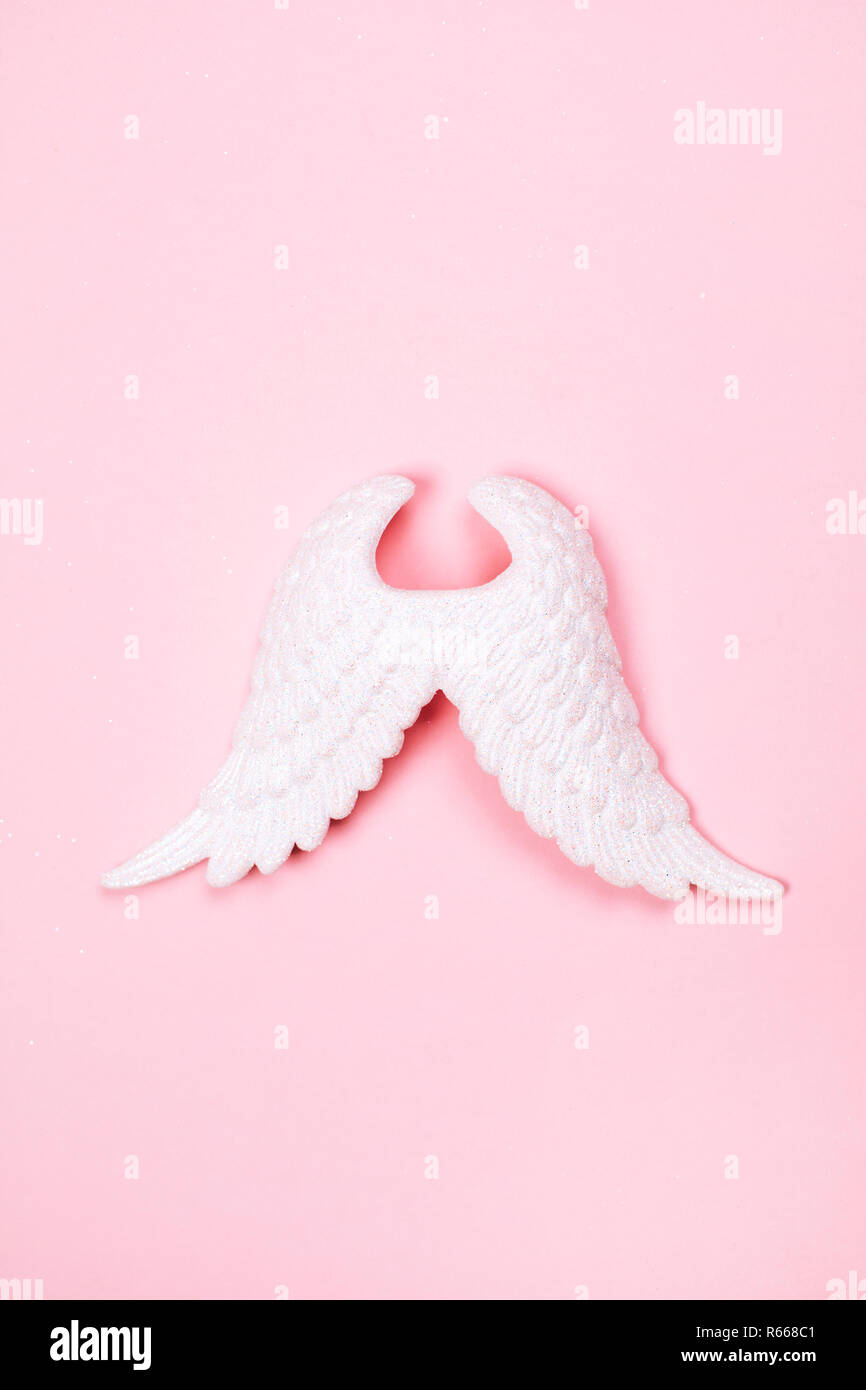 Christmas decorative white sparkling wings of angel on pink pastel  background. Macro. Festive concept Stock Photo - Alamy