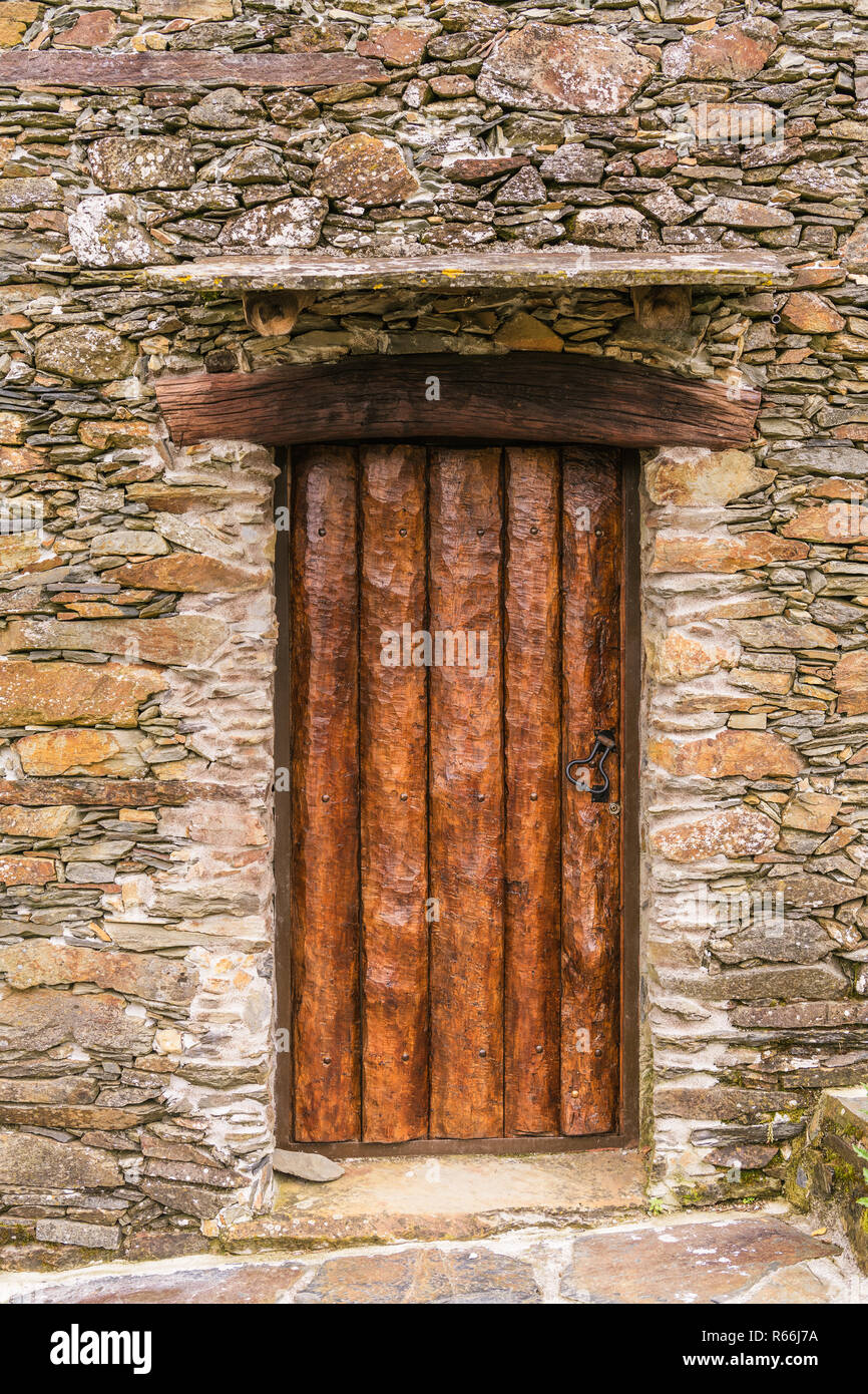 Rustic hand-hewn wood door set into a stone wall in Candal, one of Portugal's schist villages in the Aldeias do Xisto Stock Photo