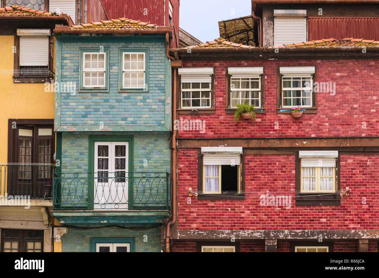 Colorful, old, weathered buildings with tiled and stucco facades in red, yellow, and blue hues in Porto, Portugal Stock Photo
