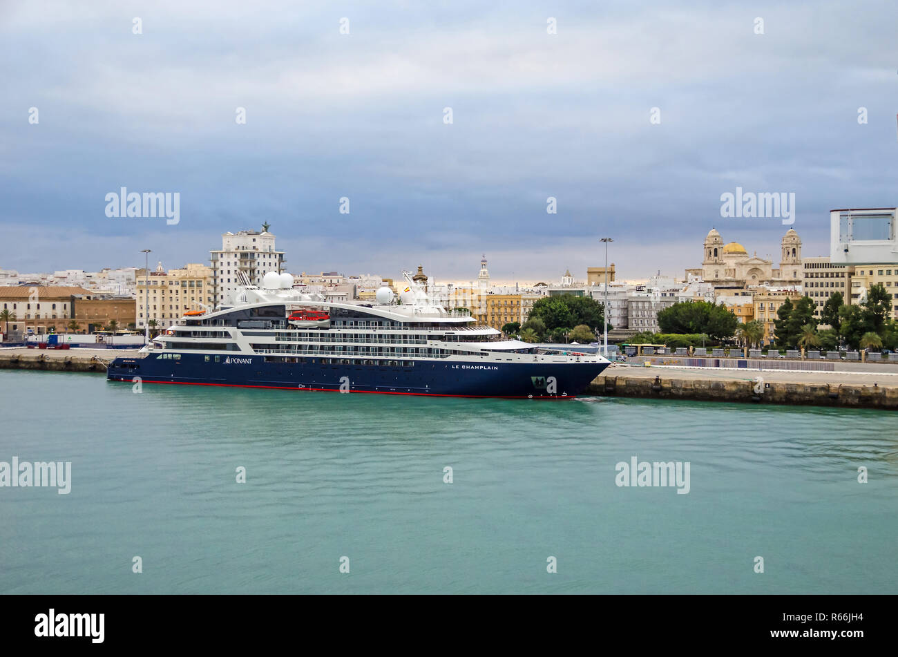 Cadiz, Spain -  November 2, 2018:  Cruise liner Le Champlain anchored  in the port of Cadiz late in the evening with the cityscape Stock Photo