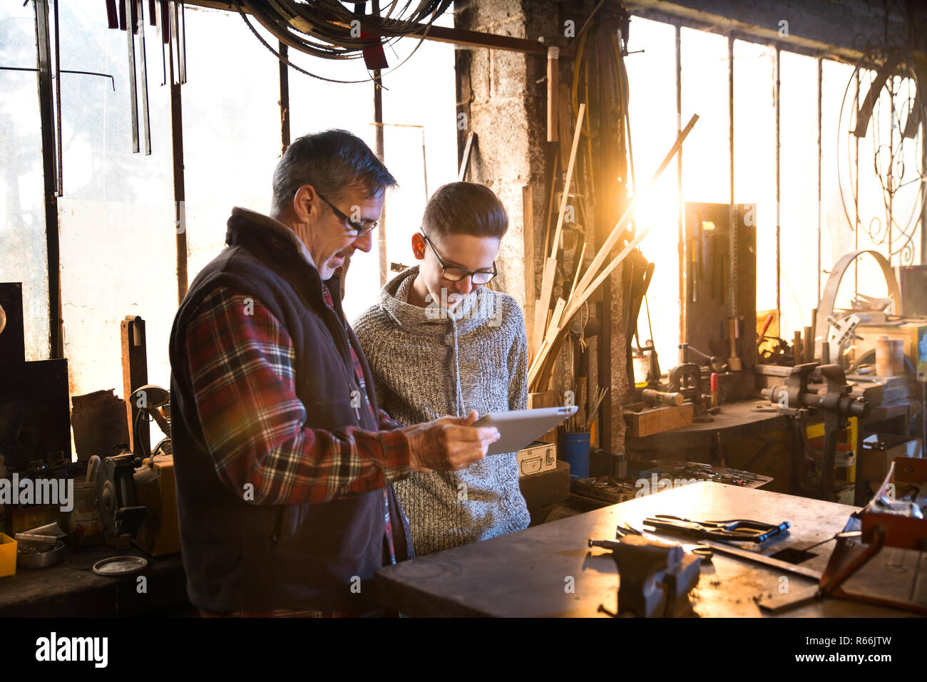 A craftsman and his young apprentice using a digital tablet Stock Photo