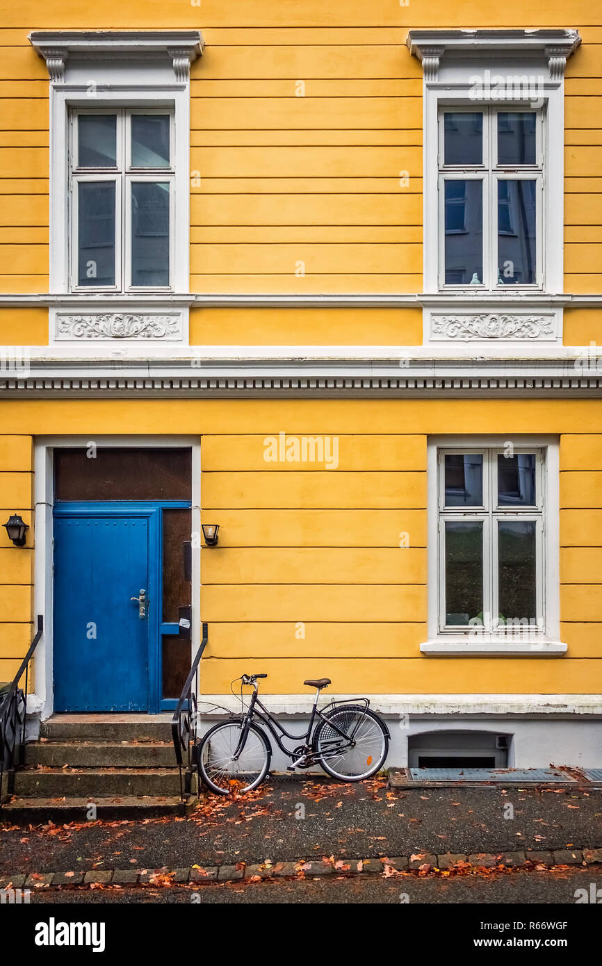Old vintage bicycle parked under the windows of an old yellow house in the Bergen Stock Photo