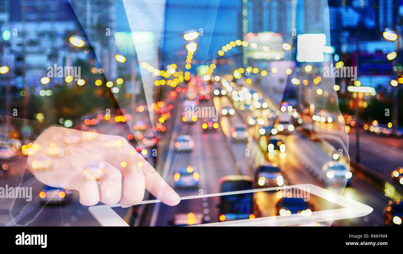 Double exposure businessman touching tablet with Evening traffic,Motion blur and bokeh effect viewed from the road bridge Stock Photo