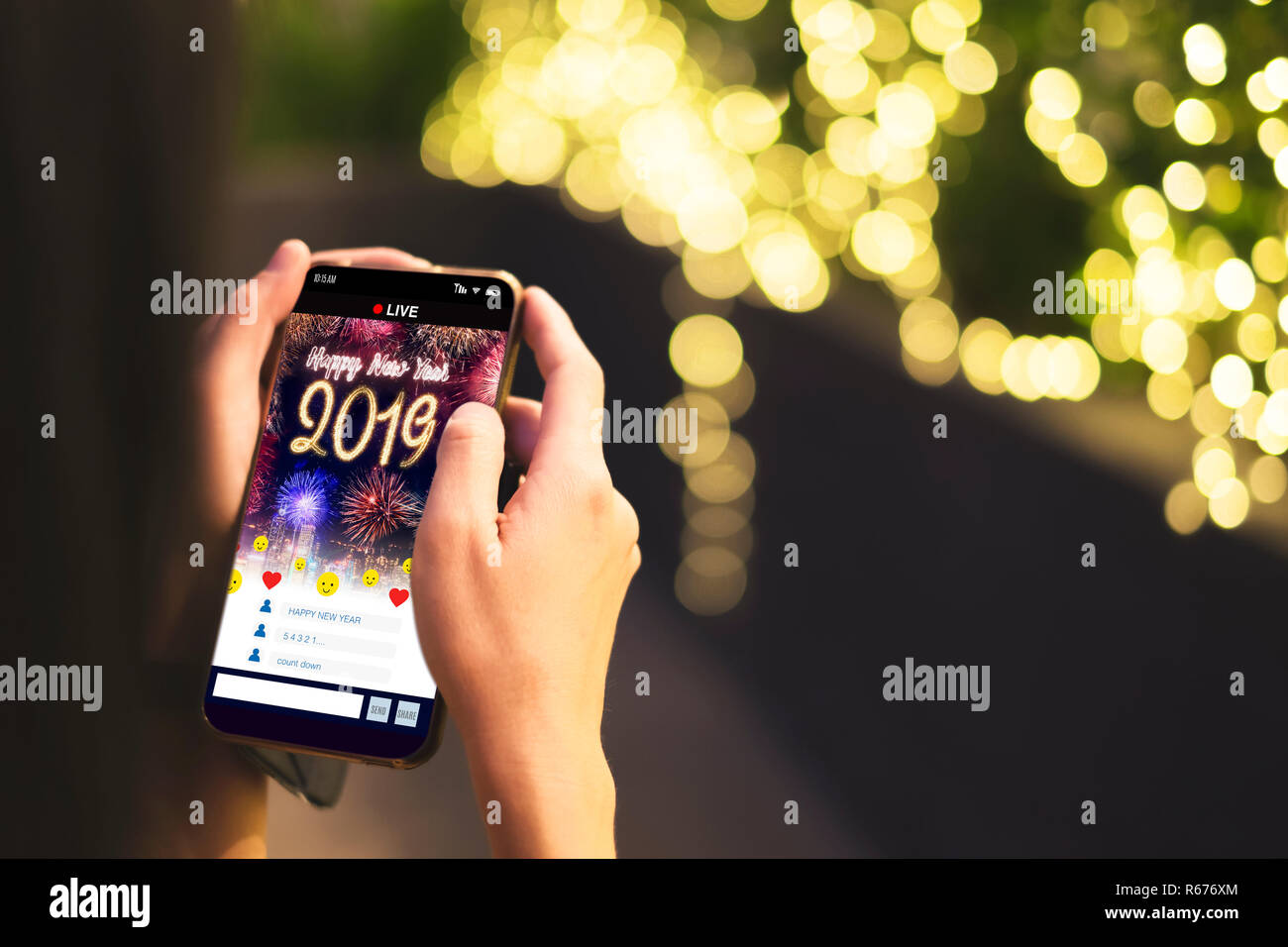 Woman Hand holding mobile see live streaming countdown to Happy new year 2019 with fireworks over cityscape on screen with light bokeh background,Digi Stock Photo