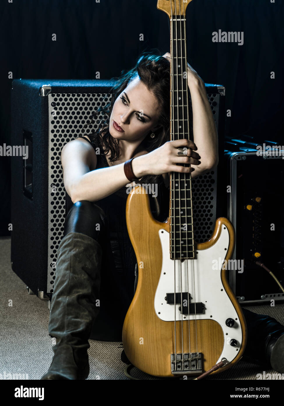 Beautiful woman bass player sitting with her amp Stock Photo