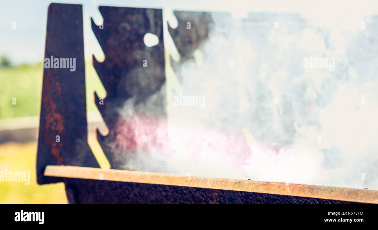 an old rusty steaming barbecue when lighting in garden Stock Photo
