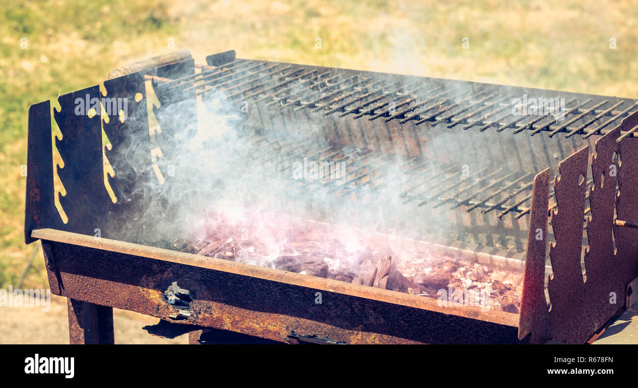 an old rusty steaming barbecue when lighting in garden Stock Photo