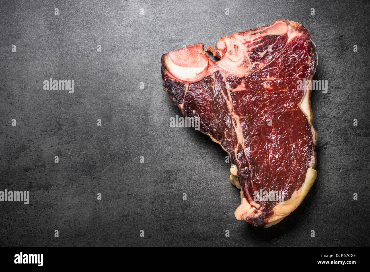 Dry aged beef steak t-bone on black slate background.  Stock Photo