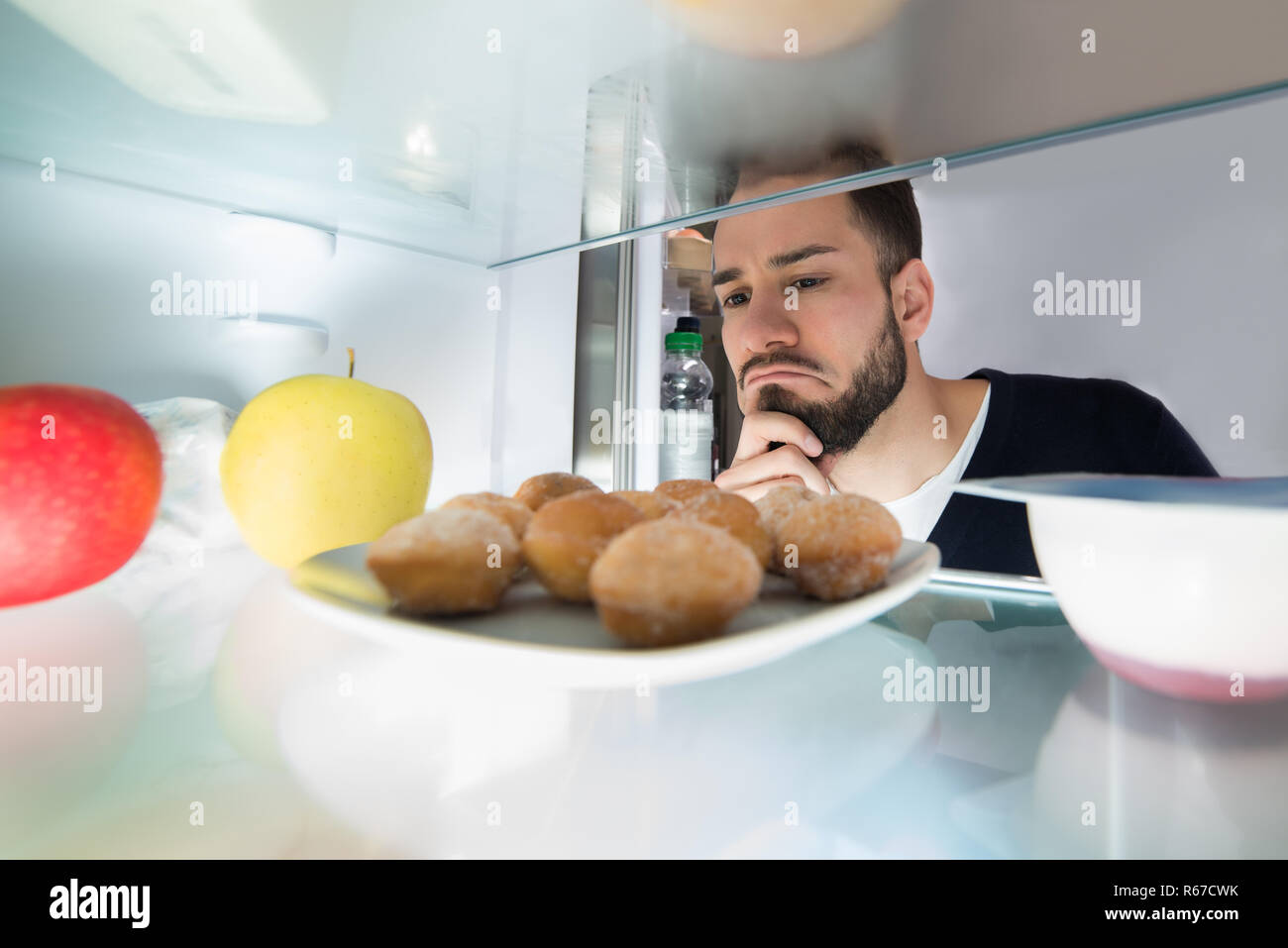 Close-up Of A Man Looking At Food Kept In Refrigerator Stock Photo
