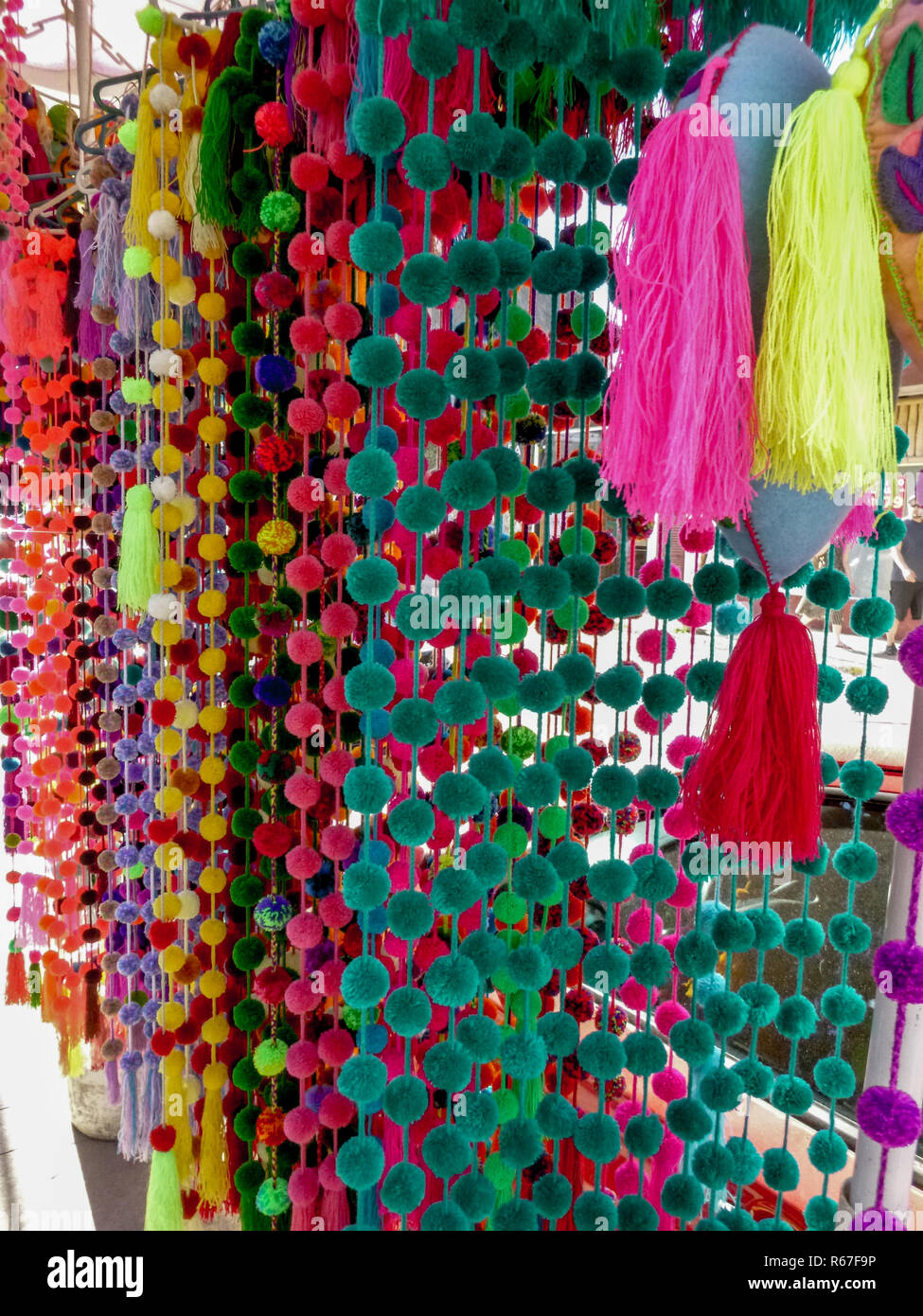 Colorful handmade yarn pom poms and tassels on display at outdoor market in Sayulita, Mexico