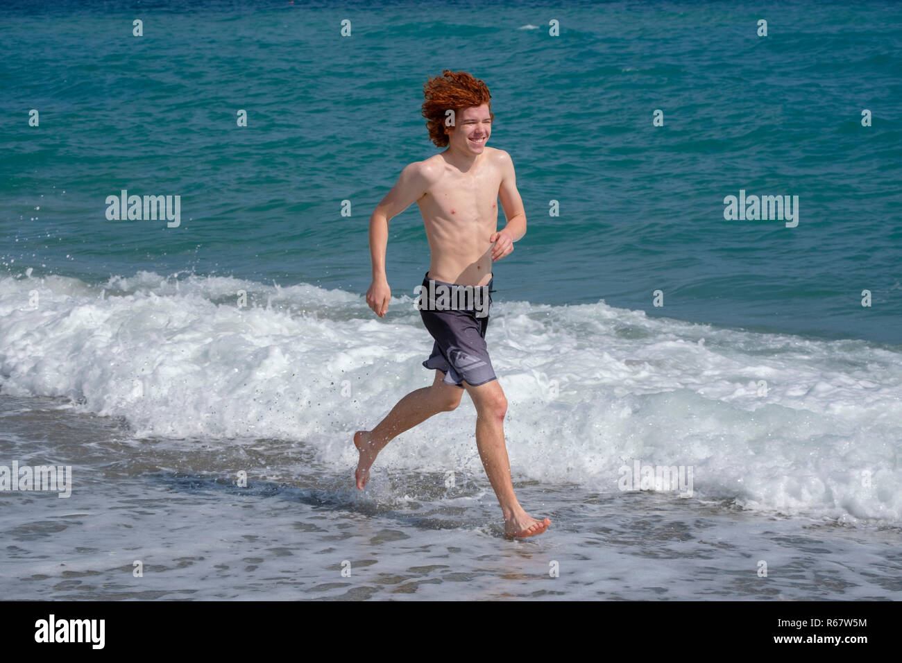 Light-skinned, red-haired teenager jogging by the sea, beach, Finale Ligure, Riviera di Ponente, Liguria, Italy Stock Photo