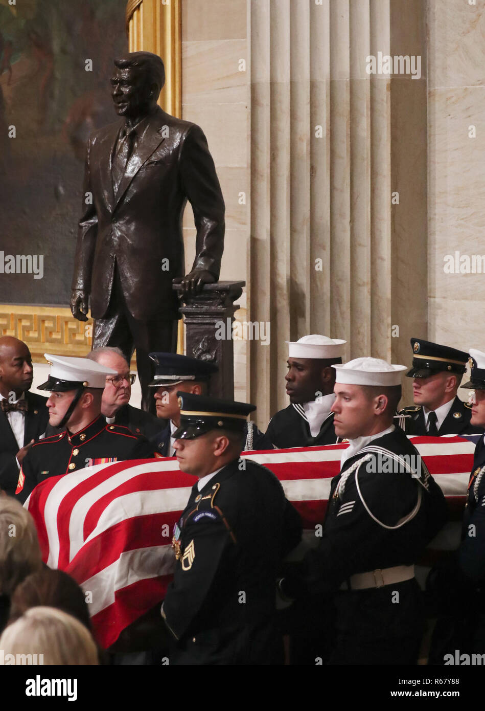 A U.S. military honor guard carries the casket of former U.S. President George H.W. Bush past the statue of former President Ronald Reagan as it arrives to lie in state in the U.S. Capitol Rotunda in Washington, U.S., December 3, 2018. Pool Via CNP/MediaPunch Stock Photo