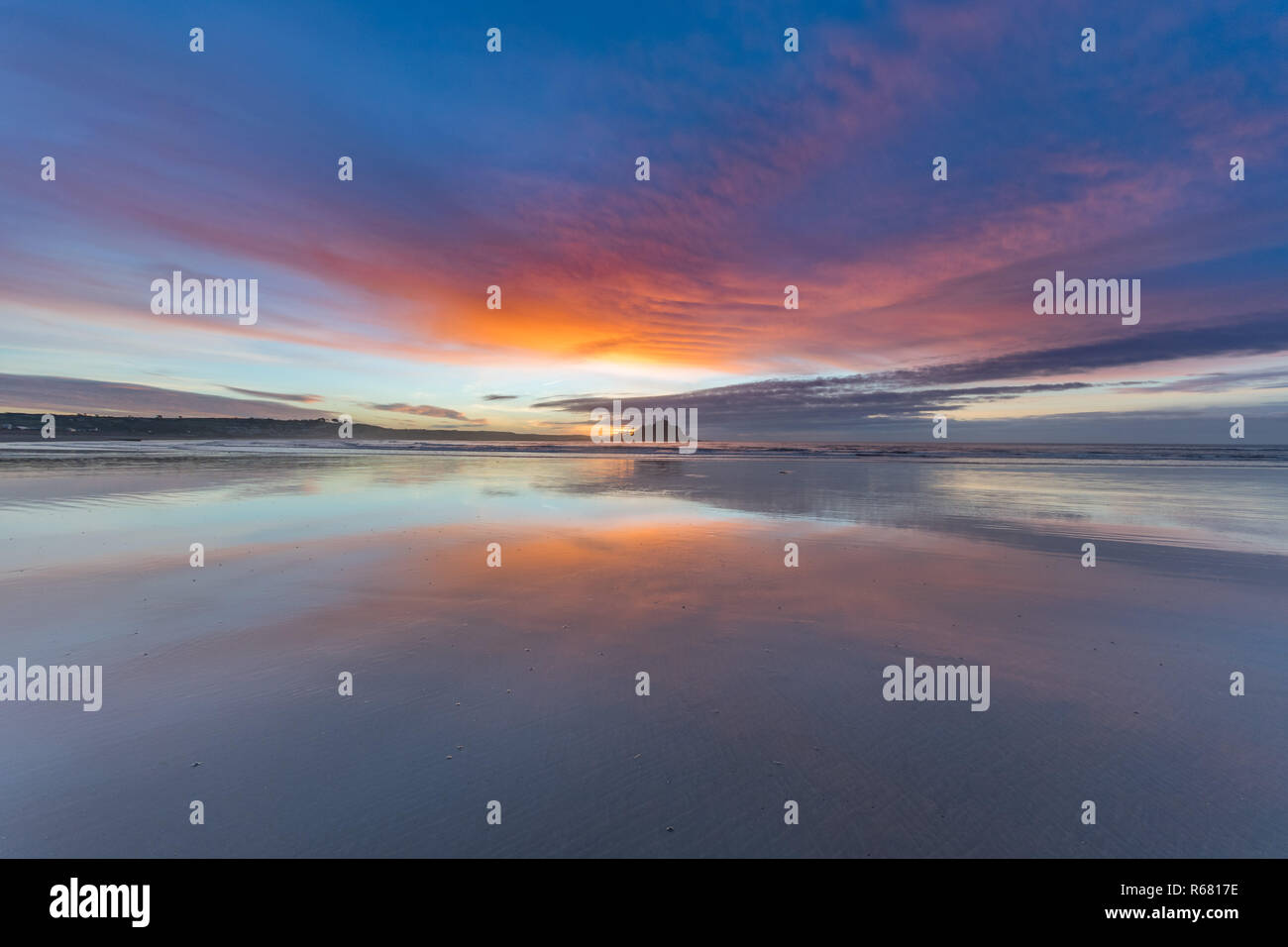 Longrock, near Marazion, Cornwall, UK. 4th December 2018. UK Weather. There was a break in the cloudy conditions this morning on the beach at Longrock, with the colour of the sky just before sunrise reflecting off the wet sand. Titan the pug was out enjoying his morning walk in dry conditions for a change. Credit: Simon Maycock/Alamy Live News Stock Photo