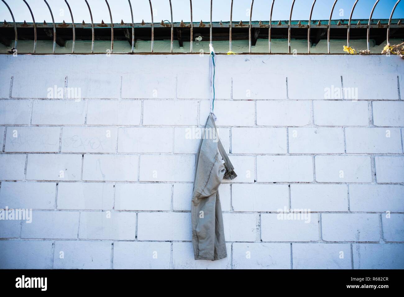 A pair of pant seen hanging on the wall at the new migrant shelter. Around 6,000 migrants are staying in a new temporary shelter where they wait for asylum in the United States. Stock Photo