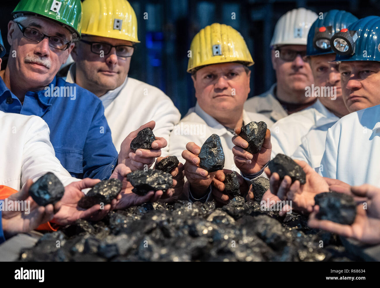 04 December 2018, North Rhine-Westphalia, Ibbenbüren: Miners are standing in front of a winding shaft of Ibbenbüren colliery with pieces of coal from the last wagon to be mined. Subsidised coal mining in Germany will be phased out at the end of 2018. The last colliery, Prosper Haniel, closes on 21.12. in Bottrop. Photo: Bernd Thissen/dpa Stock Photo