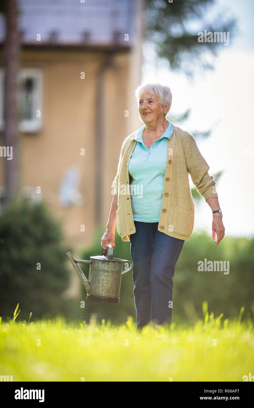 Senior woman doing some gardening in her lovely garden Stock Photo - Alamy