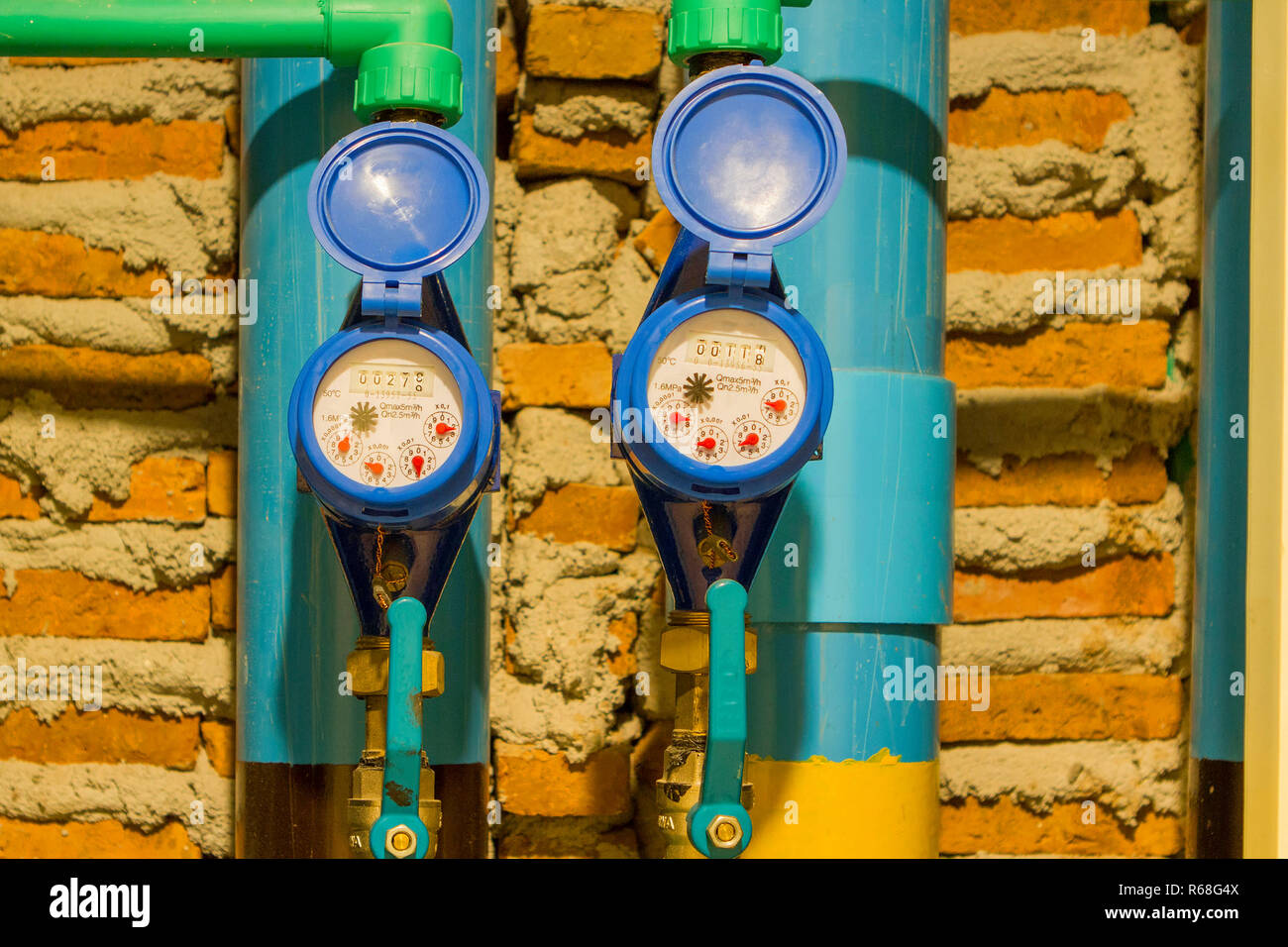 Blue water meter with water pipe, brick block background Stock Photo