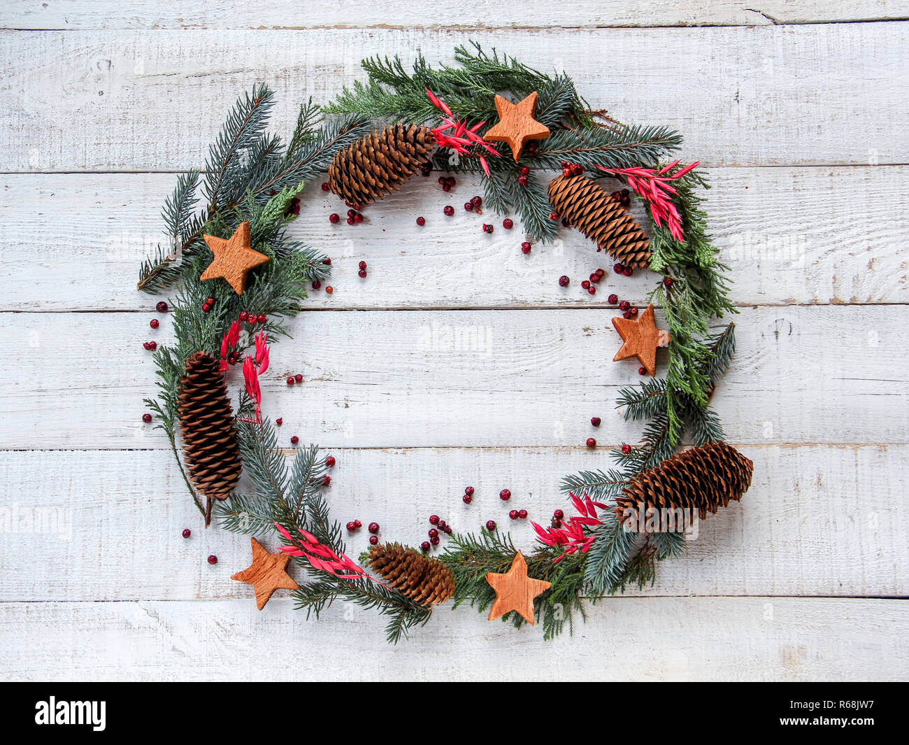Christmas wreath in flat lay style made from pine cones, coconuts stars and red berries. Space for your product or text Stock Photo